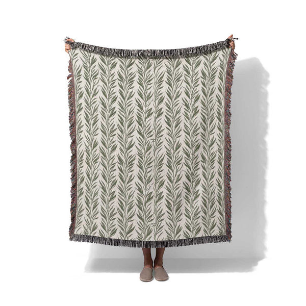 Boho woven blanket with green leaf pattern draped over a person, white background, Cuddlezzz